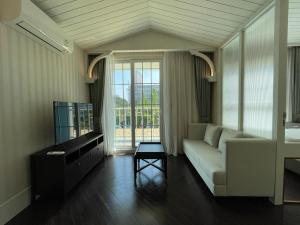 a living room with a white couch and a tv at Grand Florida芭提雅私家海滩花园公寓E206 in Na Jomtien