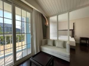 a room with a couch and a bed and windows at Grand Florida芭提雅私家海滩花园公寓E206 in Na Jomtien