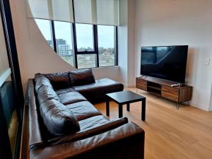 sala de estar con sofá de cuero y TV de pantalla plana en Generous 2-Bed Apartment with Great Amenities, en Melbourne