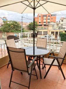 een tafel en stoelen met een parasol op een balkon bij NASS Bed & Breakfast in Cuenca
