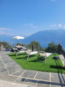 a group of chairs sitting on the grass with an umbrella at Casa Moorea - b44923 in Brione sopra Minusio