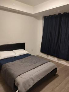 a bedroom with a large bed with a black curtain at 1 Bedroom Suite - Brand New building, Double bed in Hamilton