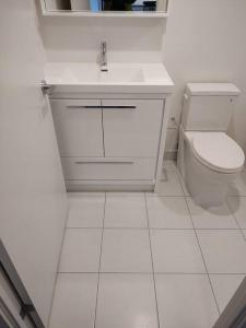 a white bathroom with a toilet and a sink at 1 Bedroom Suite - Brand New building, Double bed in Hamilton