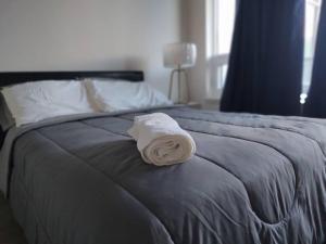 a white towel sitting on the end of a bed at 1 Bedroom Suite - Brand New building, Double bed in Hamilton