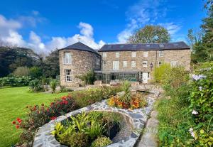 an old stone building with a garden in front of it at The Mill House in Santon