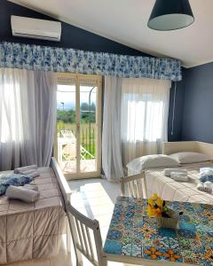 a bedroom with two beds and a table and a balcony at Villa Nadira in Giardini Naxos