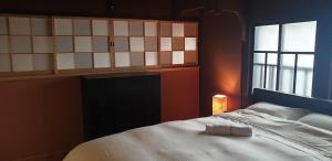 a bedroom with a white bed and a window at Johns House じょんのやど in Himeji