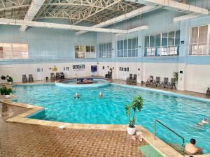 een groot zwembad met mensen in het water bij Raduga West 'Azure' Apartment in Koshkolʼ