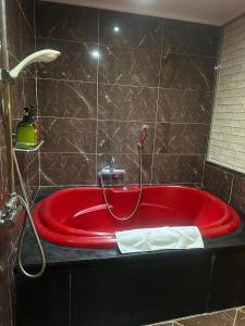 uma banheira vermelha numa casa de banho com azulejos pretos em v motel em Busan