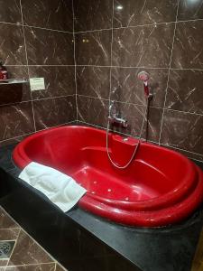 uma banheira vermelha numa casa de banho com azulejos pretos em v motel em Busan