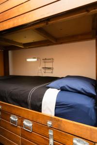 Haka Lodge Auckland في أوكلاند: سرير بطابقين مع ملاءات زرقاء وبيضاء في الغرفة