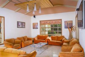 sala de estar con muebles de color naranja y ventana en JTC CLUB RESORT, en Karumattampatti