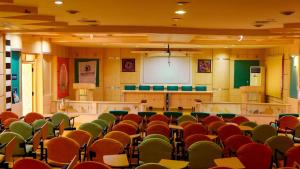 una sala de conferencias vacía con sillas y una pantalla blanca en JTC CLUB RESORT, en Karumattampatti