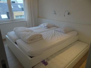 1 cama blanca con 2 almohadas y ventana en Horizon 0501 located on the sea wall, en Nieuwpoort