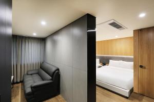 um quarto de hotel com uma cama e uma cadeira em Hotel The One em Gangneung