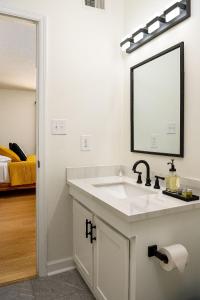 Baño blanco con lavabo y espejo en Emerald Retreat - Central & Stylish - 2 BR/2 BA en Winston-Salem
