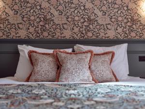a bed with four pillows and a floral wallpaper at Good Seasons Hotel Den Bosch in Den Bosch