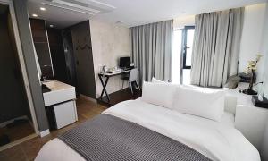 a bedroom with a large white bed and a desk at Hapjeong Circle Hotel in Seoul