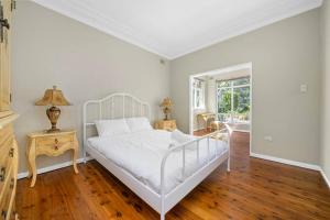 1 dormitorio con cama blanca y suelo de madera en River View Oasis: Spacious 3-Bed House with Pool en Sídney