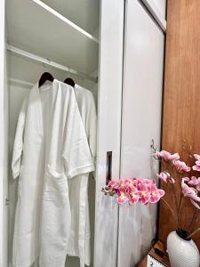 a wardrobe with white clothes and pink flowers at Kaida Apartment (凯达公寓酒店) in Bắc Ninh