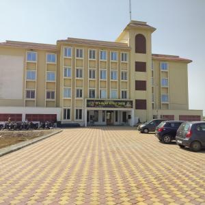 een groot gebouw met auto's geparkeerd op een parkeerplaats bij ISKCON'S GITANAGARI RETREAT CENTER VRINDAVAN in Jait