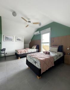 a bedroom with two beds and a ceiling fan at Melody in Saint-Paul