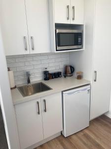 a kitchen with white cabinets and a sink and a microwave at Studio on Patete in Taupo
