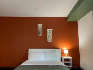 ein Schlafzimmer mit einer orangefarbenen Wand mit einem Bett und Kronleuchtern in der Unterkunft Chic and Modern unit in Los Angeles