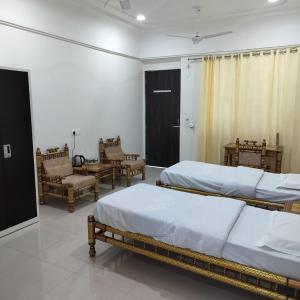 een slaapkamer met 2 bedden en stoelen in een kamer bij ISKCON'S GITANAGARI RETREAT CENTER VRINDAVAN in Jait