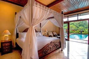 1 dormitorio con cama con dosel y piscina en The Payogan Villa Resort and Spa en Ubud