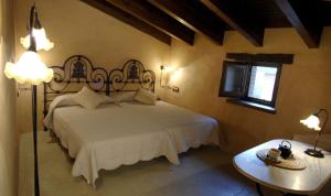 a bedroom with a large white bed and a table at La Premsa Hotel Rural in Cardona