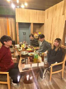 grupa ludzi siedzących przy stole w obiekcie ゲストハウスみどり w mieście Iiyama