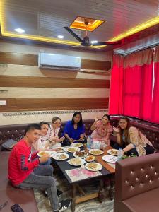 a group of people sitting around a table eating at Friends Guest House & Hostel- near TAJ MAHAL in Agra