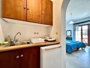 a kitchen with wooden cabinets and a sink at Nostos Plaka Beach in Plaka