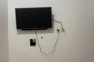 una TV a schermo piatto seduta sopra una parete di OYO 93849 Kng Homestay Syariah a Pekanbaru