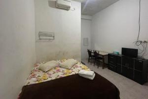 1 dormitorio con 1 cama y escritorio con ordenador en OYO 93849 Kng Homestay Syariah, en Pekanbaru