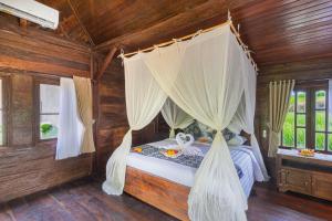 Schlafzimmer mit Himmelbett und Vorhängen in der Unterkunft Abian Ubud View in Ubud