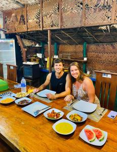 Ein Mann und eine Frau sitzen an einem Tisch mit Essen in der Unterkunft Sheran Safari House in Udawalawe