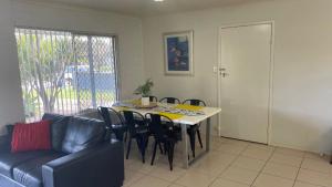 a living room with a table and chairs and a couch at Lowset home with attached Granny Flat - Doomba Dr, Bongaree in Bongaree