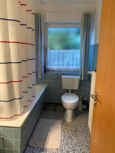 ein Bad mit einem WC, einer Badewanne und einem Fenster in der Unterkunft Wohnung mit Bergblick in Mittenwald in Mittenwald