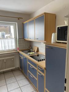 eine kleine Küche mit blauen Schränken und einer Mikrowelle in der Unterkunft Wohnung mit Bergblick in Mittenwald in Mittenwald + 2 Fotos