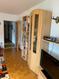 ein Wohnzimmer mit Bücherregalen und einem Flachbildfernseher in der Unterkunft Wohnung mit Bergblick in Mittenwald in Mittenwald