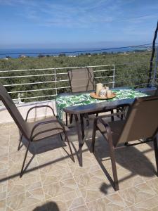 een tafel en stoelen op een patio met uitzicht op de oceaan bij SUN GARDEN in Skala Sotiros