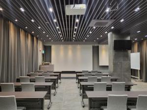 a conference room with tables and chairs and a screen at Centro Hotel in Chilgok