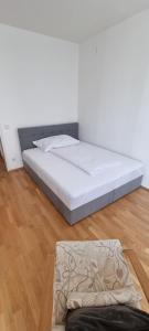 a white bed in a room with a wooden floor at Haus Blindenmarkt in Amstetten