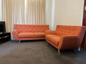 2 orangefarbene Sofas in einem Zimmer mit einem TV in der Unterkunft Cheerful 2 bedroom house with a beautiful veranda in Geelong