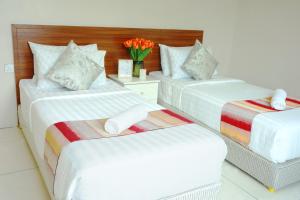 three beds in a room with a vase of flowers at Simfoni Resort Langkawi by Perfect Host in Kuah