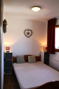 een slaapkamer met een bed en een klok aan de muur bij Les Chalets De Superd Ancolie - 2 Pièces pour 6 Personnes 741 in Le Dévoluy