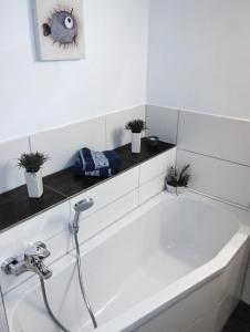 a white bath tub in a bathroom with potted plants at Huus am Darß in Fuhlendorf +25 photos