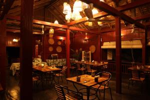 un restaurante con mesas de madera y sillas en una habitación en Sambor Village Hotel en Kompong Thom